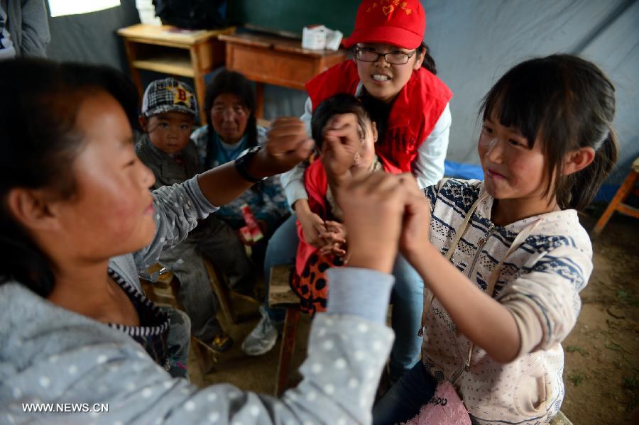 A volunteer plays with children in a "Tent School" in quake-stricken Yongxing Village of Minxian County, northwest China's Gansu Province, July 24, 2013. 10 university student volunteers teach various courses for those in need in the "Tent School" in quake-stricken Yongxing Village on Wednesday. (Xinhua/Zhang Meng)