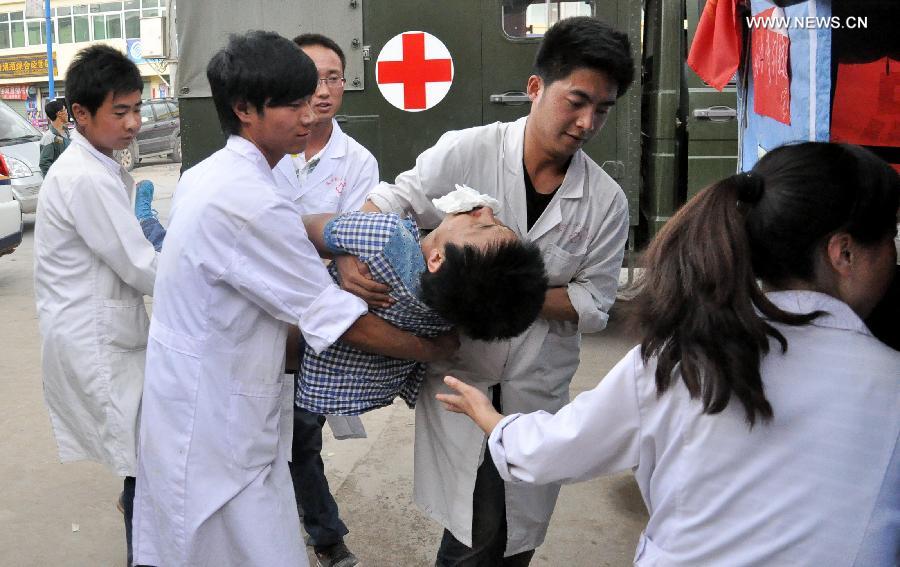 Doctors carry an injured man to a makeshift clinic in Meichuan Town of Minxian County, northwest China's Gansu Province, July 24, 2013. By far, makeshift clinics have been set up to offer basic medical treatment in quake-hit towns. And severely injured people have been sent to hospitals for better care in the county seat of Minxian, Dingxi City and Lanzhou City, capital of Gansu. (Xinhua/Guo Gang)