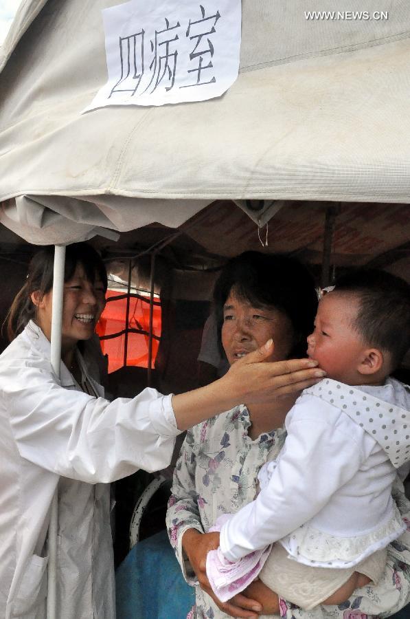 A doctor comforts a child in a makeshift clinic in Meichuan Town of Minxian County, northwest China's Gansu Province, July 24, 2013. By far, makeshift clinics have been set up to offer basic medical treatment in quake-hit towns. And severely injured people have been sent to hospitals for better care in the county seat of Minxian, Dingxi City and Lanzhou City, capital of Gansu. (Xinhua/Guo Gang)