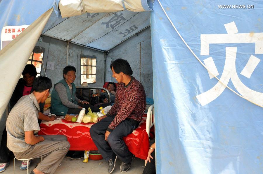 Patients with minor injuries chat in a makeshift clinic in Meichuan Town of Minxian County, northwest China's Gansu Province, July 24, 2013. By far, makeshift clinics have been set up to offer basic medical treatment in quake-hit towns. And severely injured people have been sent to hospitals for better care in the county seat of Minxian, Dingxi City and Lanzhou City, capital of Gansu. (Xinhua/Guo Gang) 