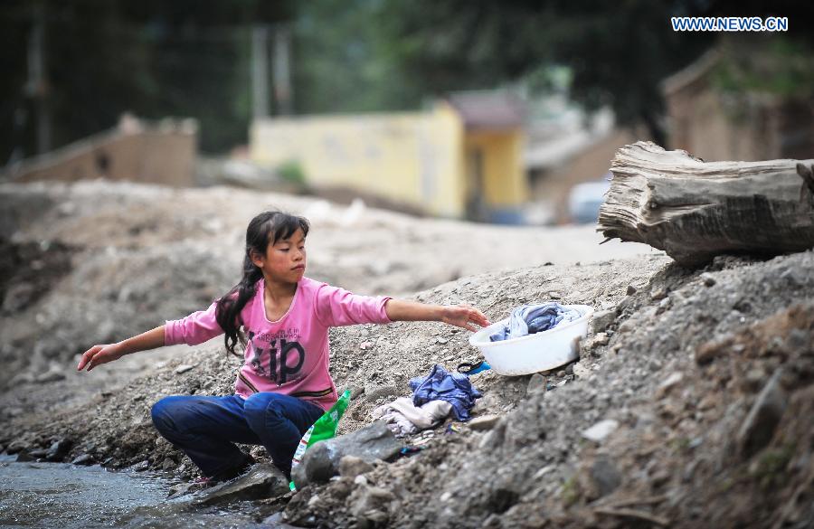 A child does laundry in Hetuo Township of quake-hit Minxian County, northwest China's Gansu Province, July 24, 2013. A 6.6-magnitude quake hit northwest China's Gansu Province on Monday morning, leaving 95 dead and 1,001 injured. (Xinhua/Liu Xiao)