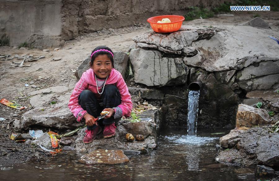 A girl peels potatoes by a ditch in Shendu Township of quake-hit Minxian County, northwest China's Gansu Province, July 24, 2013. A 6.6-magnitude quake hit northwest China's Gansu Province on Monday morning, leaving 95 dead and 1,001 injured. (Xinhua/Liu Xiao) 