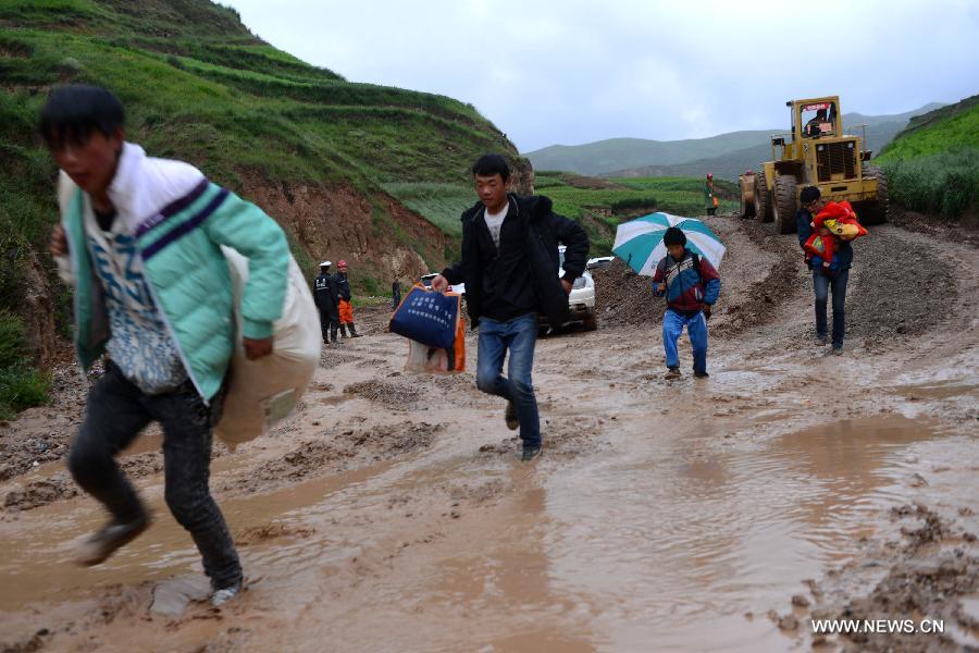 Villagers walk in a muddy road in Meichuan Township of quake-hit Minxian County, northwest China's Gansu Province, July 25, 2013. Precautions have been taken to prevent second disasters since a torrential rainfall started on Wednesday in the quake-stricken area. (Xinhua/Jin Liangkuai)