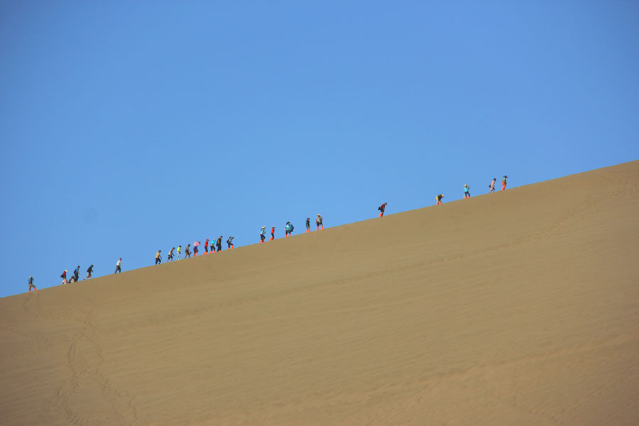 A line of people climb up one of Mingsha Mountain's dunes. (CRIENGLISH.com/William Wang)