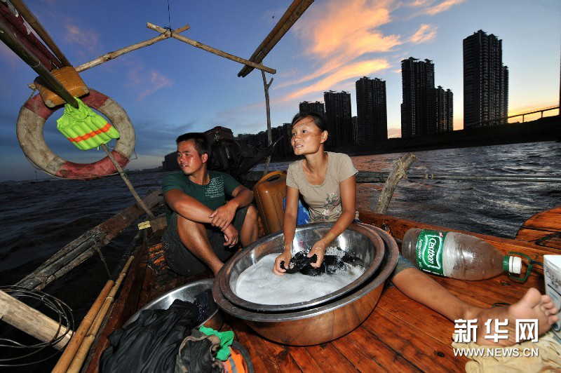 Early in the morning, Yi talks to his wife when waiting for the right time of hauling the net. (Photo by Long Hongtao/ Xinhua)