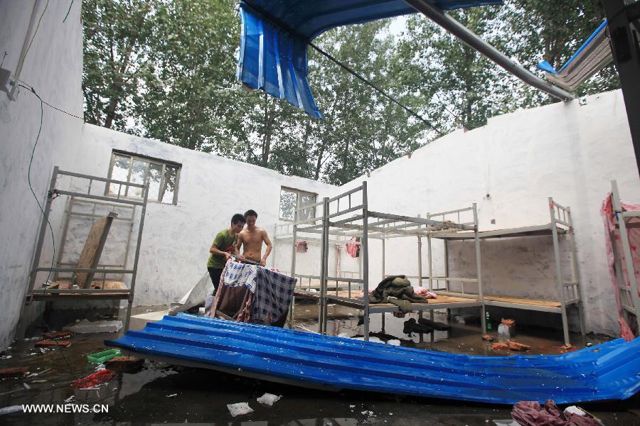 Workers transfer their holdings in a damaged house in Liaocheng City, east China's Shandong Province, July 26, 2013. Rainstorms hit the city from Thursday evening to Friday. (Xinhua/Xiao Minglei)