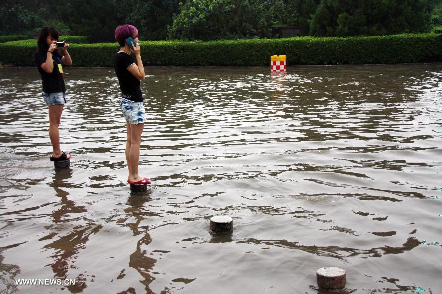 Citizens wait for bus on a flooded road in Liaocheng City, east China's Shandong Province, July 26, 2013. Rainstorms hit the city from Thursday evening to Friday. (Xinhua/Kong Xiaozheng)