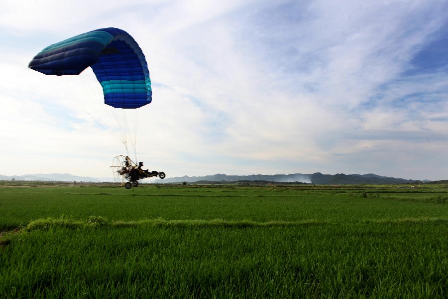 A paramotor sprays pesticide at the Hongguang Farm in Duchang County, east China's Jiangxi Province, July 26, 2013. Paramotors are used to spray pesticide in the air in Duchang County, since it's the critical period to prevent and wipe out paddy rice diseases and insect pests. (Xinhua/Fu Jianbin)