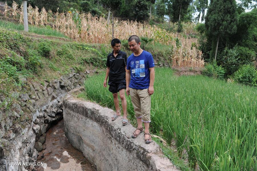 Qiu Zhiming (R), town chief of Gaoqiao, checks a dried up well in Dongmu Village, Gaoqiao, Tongxi County, southwest China's Guizhou Province, July 26, 2013. Lingering droughts in Guizhou have affected more than 8.37 million people, local authorities said Friday. Over 1 million people lack adequate supplies of drinking water, and a total of 541,200 hectares of farmland is also affected by the drought, the provincial government said. (Xinhua/Wang Nian) 