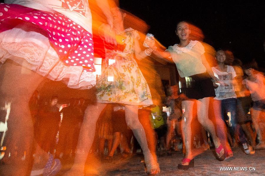 Tourists take part in a campfire party at Guifeng Mountain in Macheng City, central China's Hubei Province, July 27, 2013. A lot of citizens chose to escape the heat in the mountains due to the continuous scorching weather in Hubei province in recent days. (Xinhua/Cheng Min)  