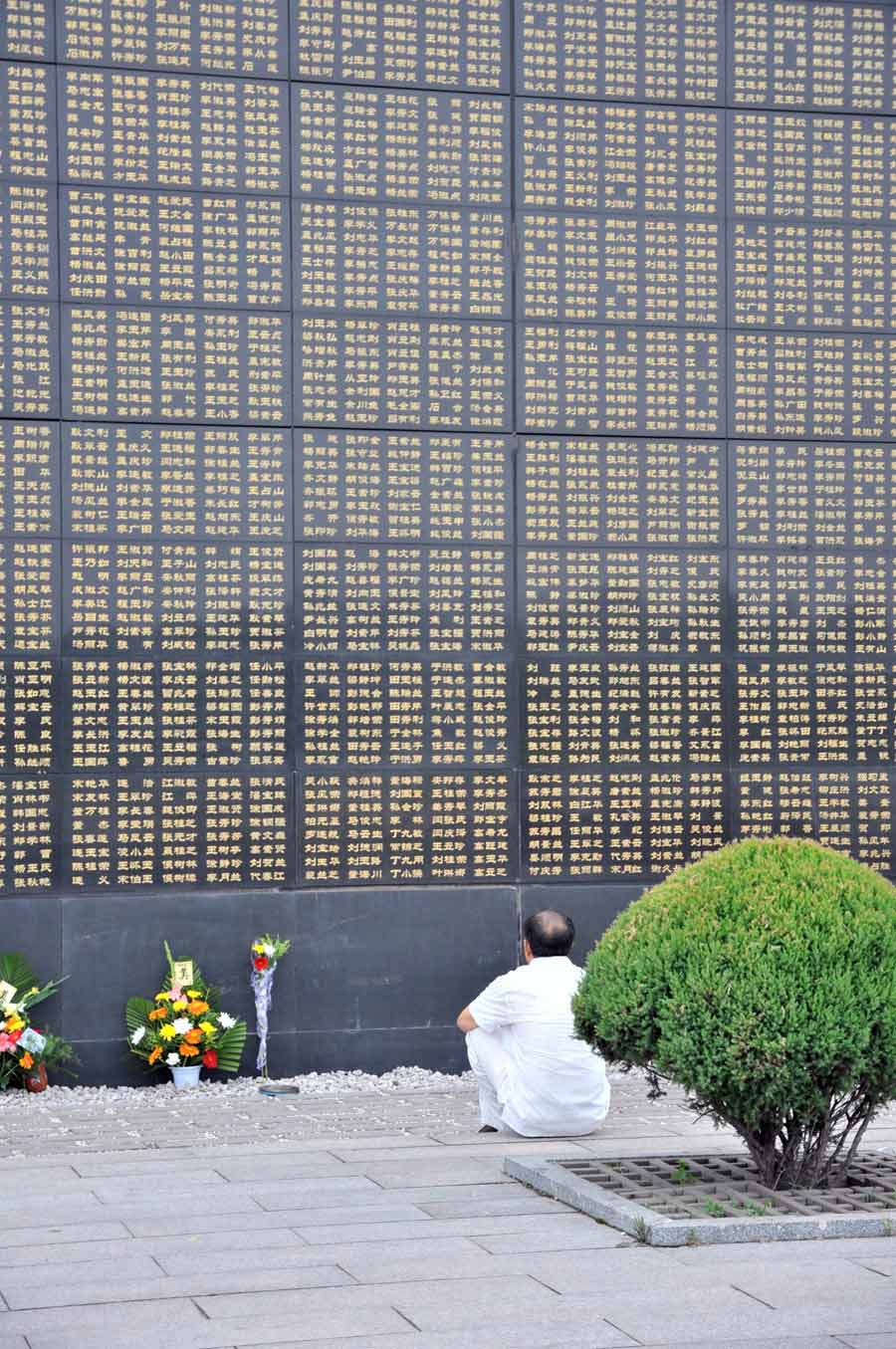 A man mourns for his relatives died in the 1976 Tangshan earthquake in front of the memorial wall in Tangshan, north China's Hebei Province, July 28, 2013. Local residents came to the memorial park on Sunday to commemorate the 37th anniversary of the Tangshan earthquake. (Photo/Xinhua)