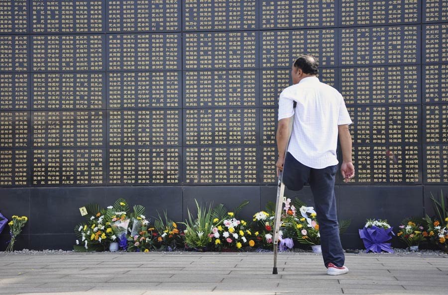 A man mourns for his relatives died in the 1976 Tangshan earthquake in front of the memorial wall in Tangshan, north China's Hebei Province, July 28, 2013. Local residents came to the memorial park on Sunday to commemorate the 37th anniversary of the Tangshan earthquake. (Photo/Xinhua)