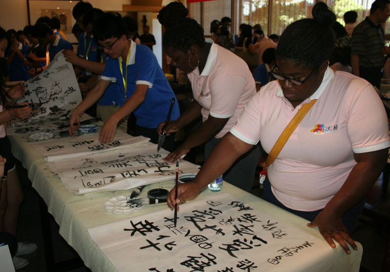 Two US students practice writing Chinese calligraphy after listening to a lecture given by Zheng Xiaohua, a famous Chinese calligrapher at the School of Arts in Renmin University on Wednesday, July 24, 2013. [Photo: CRIENGLISH.com]