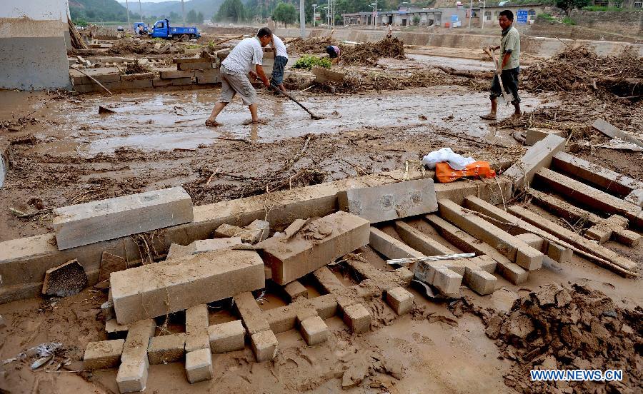 People clean silt in front of the house in Yunyan Town, Yichuan County of northwest China's Shaanxi Province, July 28, 2013. Lasting Heavy rainfall in July has affected 13 counties in Yan'an City. (Xinhua/Qi Xiaojun) 