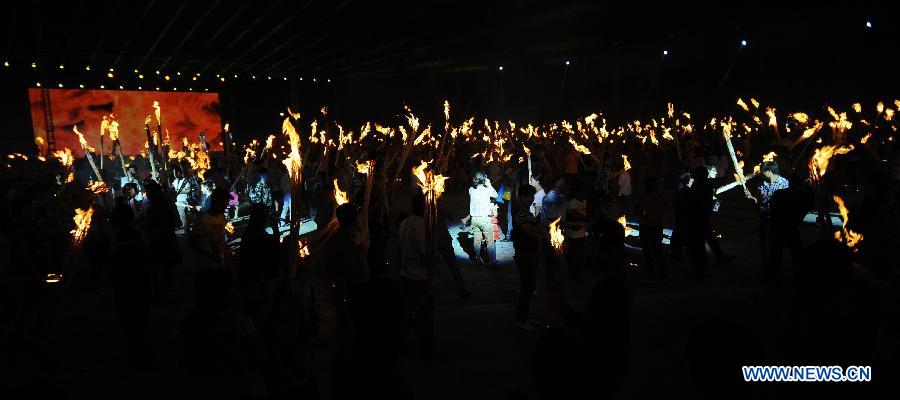 Tourists hold burning torches to celebrate the Torch Festival at Yunnan Nationalities Village in Kunming City, southwest China's Yunnan Province, July 28, 2013. The Torch Festival, which falls around the 24th day of the sixth Chinese lunar month every year, is the traditional holiday of the Yi ethnic group and some other ethnic groups. (Xinhua/Qin Lang)