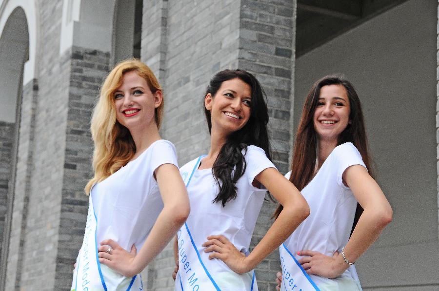 Contestants of the 23rd World Model Organization (WMO) world super model contest finals pose for pictures during a themed photography activity at the Dongjiang shore in north China's Tianjin Municipality, July 28, 2013. In total 37 super models from more than 20 countries and regions all over the world will compete during the final of the 23rd WMO super model contest on Aug. 2, 2013 in Tianjin. (Xinhua/Xue Liqiang)