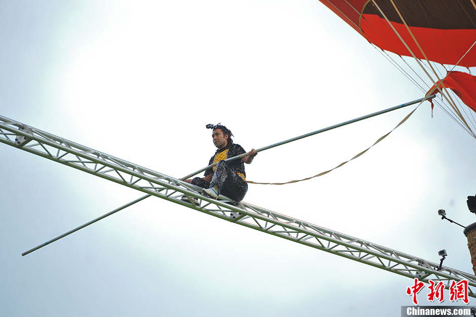 Askar, 40, from Xinjiang, has set a new world record after walking on a tightrope between two moving balloons at high altitude in Shilin, southwest China’s Yunan province on July 30, 2013. He has set World Guinness records for five times. With the help of a steel beam with a diameter of 50 millimeters Askar covered a distance of 18 meters in the air on the rope. (Photo by Ren Dong/ Chinanews.com)