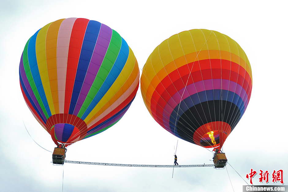 Askar, 40, from Xinjiang, has set a new world record after walking on a tightrope between two moving balloons at high altitude in Shilin, southwest China’s Yunan province on July 30, 2013. He has set World Guinness records for five times. With the help of a steel beam with a diameter of 50 millimeters Askar covered a distance of 18 meters in the air on the rope. (Photo by Ren Dong/ Chinanews.com)