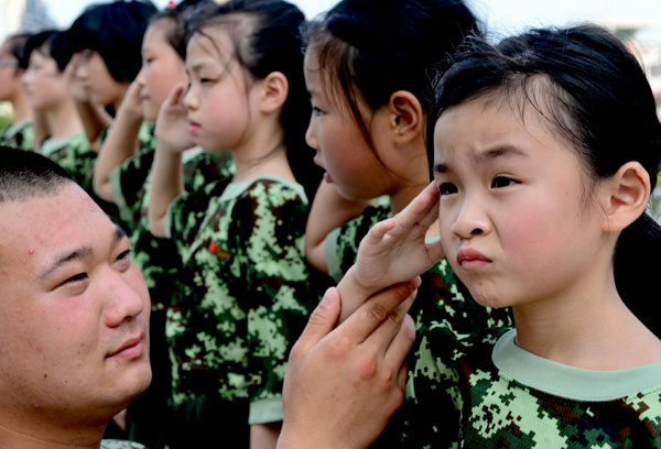 Zheng Yunchu, 7, practices a military salute under instruction in Fuqing on July 29, 2013. [Photo/Xinhua]