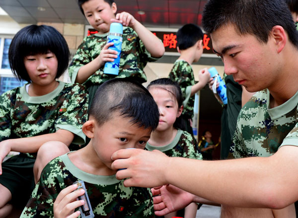 He Xinchen, 10, takes medicine to help relieve the summer heat in the camp, July 29, 2013. [Photo/Xinhua]