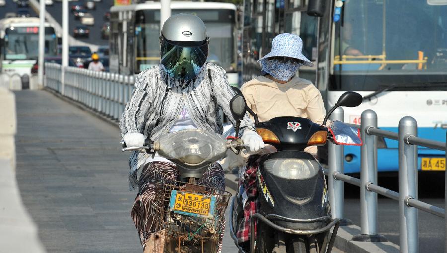 Citizens travel in the burning sun in Changsha, capital of central China's Hunan Province, July 30, 2013. High temperatures sustained in the past month in Changsha and will continue in the coming 4 days. (Xinhua/Long Hongtao)