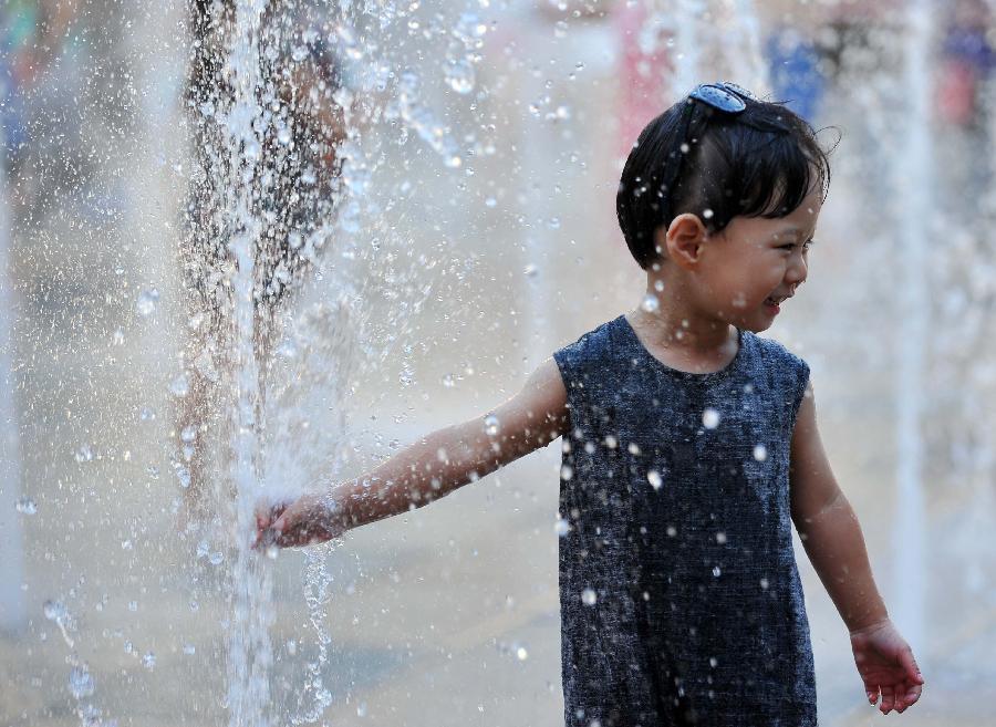 A little girl plays with water near a fountain in Sanlitun of Beijing, capital of China, July 30, 2013. The temperature in most parts of Beijing climbed as high as 34 degrees Celsius Tuesday afternoon. The China Meteorological Administration has launched a level two emergency response to heat for the first time this year on Tuesday, covering regions including east China's Anhui, Jiangsu, Zhejiang and Jiangxi,central China's Hunan and Hubei, south China's Fujian, and Shanghai and Chongqing municipalities. (Xinhua/Chen Yehua)