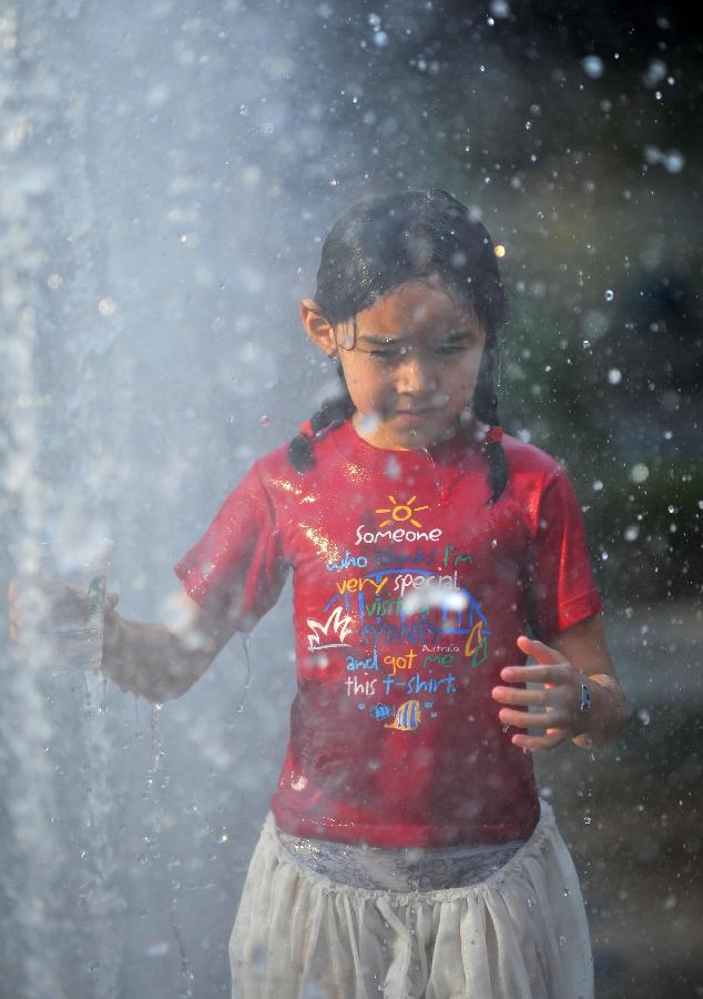 A little girl plays with water near a fountain in Sanlitun of Beijing, capital of China, July 30, 2013. The temperature in most parts of Beijing climbed as high as 34 degrees Celsius Tuesday afternoon. The China Meteorological Administration has launched a level two emergency response to heat for the first time this year on Tuesday, covering regions including east China's Anhui, Jiangsu, Zhejiang and Jiangxi,central China's Hunan and Hubei, south China's Fujian, and Shanghai and Chongqing municipalities. (Xinhua/Chen Yehua)