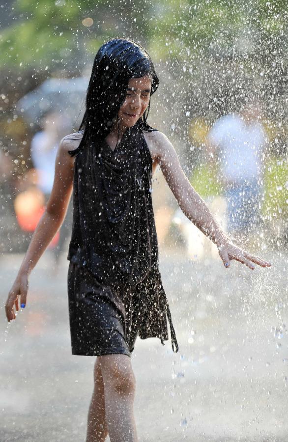 A little girl plays with water near a fountain in Sanlitun of Beijing, capital of China, July 30, 2013. The temperature in most parts of Beijing climbed as high as 34 degrees Celsius Tuesday afternoon. The China Meteorological Administration has launched a level two emergency response to heat for the first time this year on Tuesday, covering regions including east China's Anhui, Jiangsu, Zhejiang and Jiangxi,central China's Hunan and Hubei, south China's Fujian, and Shanghai and Chongqing municipalities. (Xinhua/Chen Yehua)