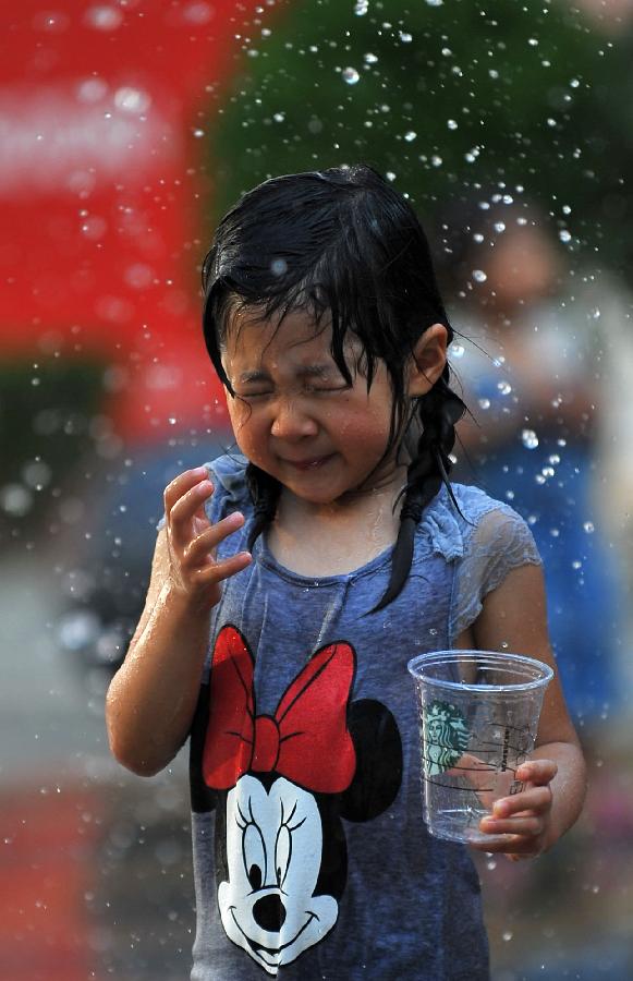 A little girl plays with water near a fountain in Sanlitun of Beijing, capital of China, July 30, 2013. The temperature in most parts of Beijing climbed as high as 34 degrees Celsius Tuesday afternoon. The China Meteorological Administration has launched a level two emergency response to heat for the first time this year on Tuesday, covering regions including east China's Anhui, Jiangsu, Zhejiang and Jiangxi,central China's Hunan and Hubei, south China's Fujian, and Shanghai and Chongqing municipalities. (Xinhua/Chen Yehua)