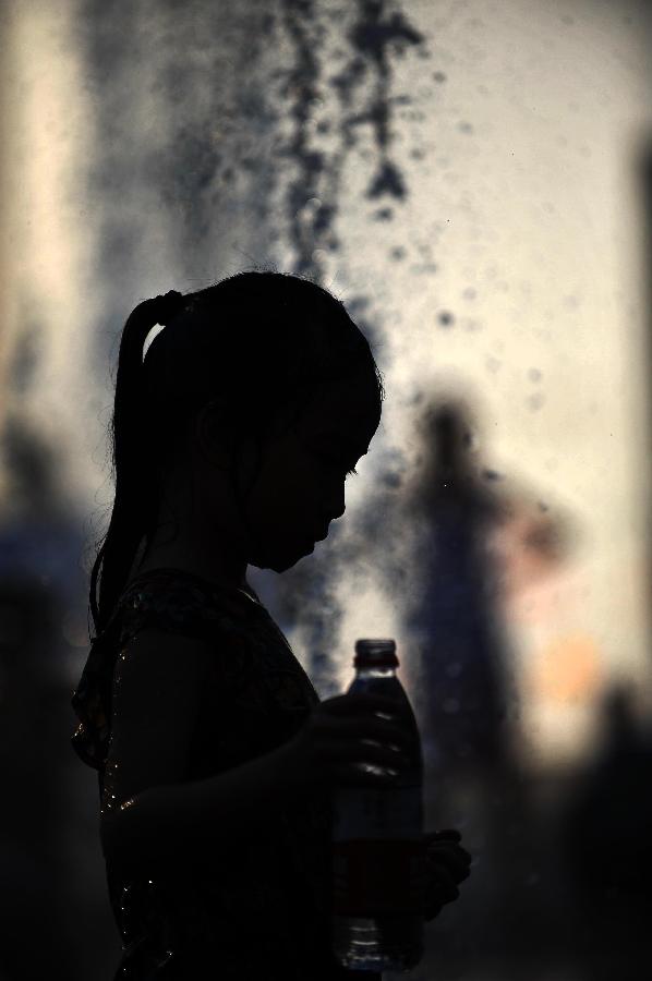 A little girl plays with water near a fountain in Sanlitun of Beijing, capital of China, July 30, 2013. The temperature in most parts of Beijing climbed as high as 34 degrees Celsius Tuesday afternoon. The China Meteorological Administration has launched a level two emergency response to heat for the first time this year on Tuesday, covering regions including east China's Anhui, Jiangsu, Zhejiang and Jiangxi,central China's Hunan and Hubei, south China's Fujian, and Shanghai and Chongqing municipalities. (Xinhua/Chen Yehua)