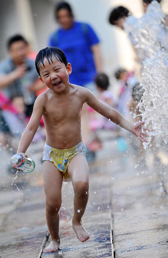 A little boy plays with water near a fountain in Sanlitun of Beijing, capital of China, July 30, 2013. The temperature in most parts of Beijing climbed as high as 34 degrees Celsius Tuesday afternoon. The China Meteorological Administration has launched a level two emergency response to heat for the first time this year on Tuesday, covering regions including east China's Anhui, Jiangsu, Zhejiang and Jiangxi,central China's Hunan and Hubei, south China's Fujian, and Shanghai and Chongqing municipalities. (Xinhua/Chen Yehua)