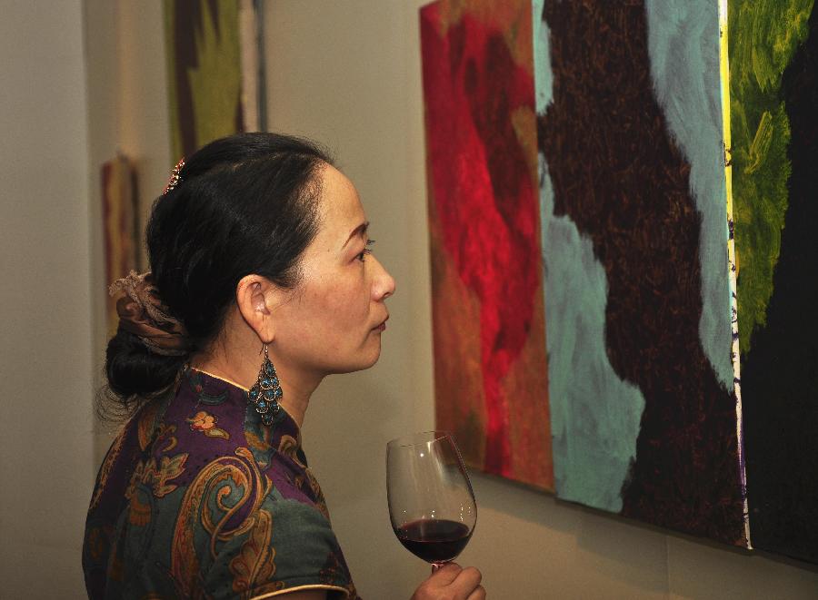 A visitor views art works at the exhibition "The Strength of Natural Impulses" in Beijing, capital of China, July 30, 2013. Jointly contributed by French artist Francois Bossiere and four Chinese artists Zhang Sen, Zhang Yuqing, Sun Qianwei and Xie Hong, the exhibition concerned with visual art will be held from July 30 to Aug. 6 in Beijing. (Xinhua/Wang Jingqiang)