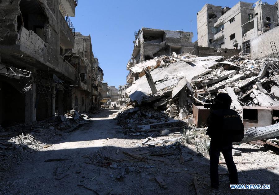 A Chinese journalist works in a steet of al-Khalidieh district in central Homs province, Syria, July 30, 2013. The Syrian army announced Monday that its troops successfully regained full control over the strategic al-Khalidieh district in central Homs province after a series of precise operations there, according to the state-TV. (Xinhua/Zhang Naijie)