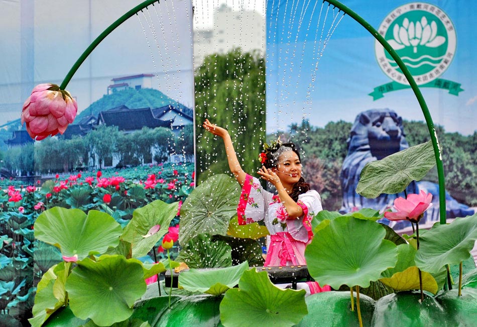 On July 23, the actors from an art troupe perform dances in lotus garden, Qinghuang Island, north China’s Hebei province. Lotus in full blossom attracted many visitors to lotus garden. (Xinhua/Yang Shiyao)