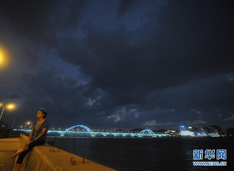 A woman takes rests by the side of Qiantang River, enjoying a slice coolness brought by the thunderstorm. Temperatures in many regions in Zhejiang had exceeded 40 degrees Celsius for many days since July, with average precipitation reduced 70 percent. (Xinhua/Wang Dingchang)