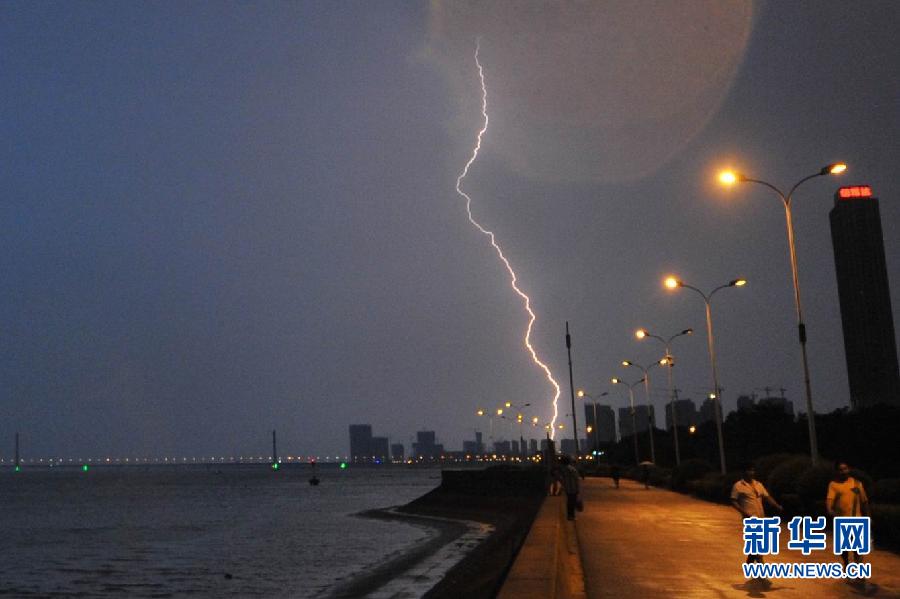 Several people walk in rain on the bank of the Qiantang River. Temperatures in many regions in Zhejiang had exceeded 40 degrees Celsius for many days since July, with average precipitation reduced 70 percent. (Xinhua/Wang Dingchang)