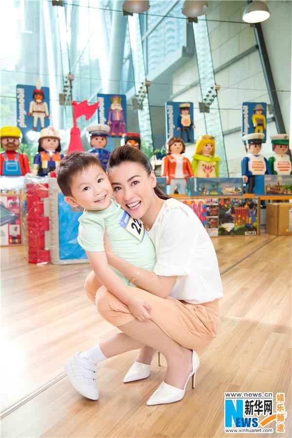 Chinese actress Cecilia Cheung poses for photos of an advertisement with a cute boy. (Photo/Xinhua)