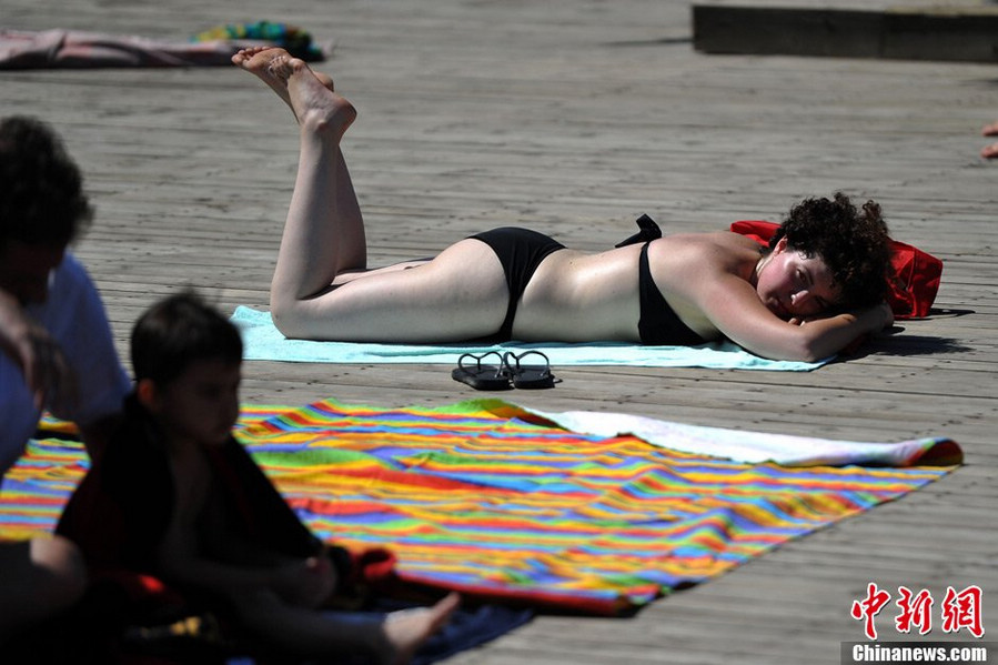 Tourists swarm to the bathing beach in Beijing's Chaoyang Park to escape the stifling heat on July 28, 2013. On the same day, the city's weather authorities issued this summer's second orange high-temperature alert. (Chinanews.com)