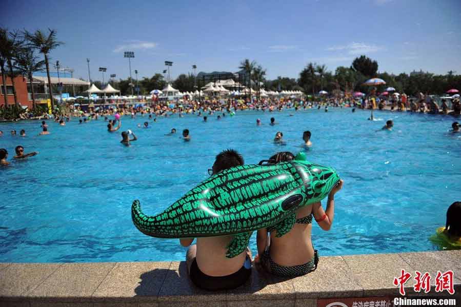 Tourists swarm to the bathing beach in Beijing's Chaoyang Park to escape the stifling heat on July 28, 2013. On the same day, the city's weather authorities issued this summer's second orange high-temperature alert. (Chinanews.com)