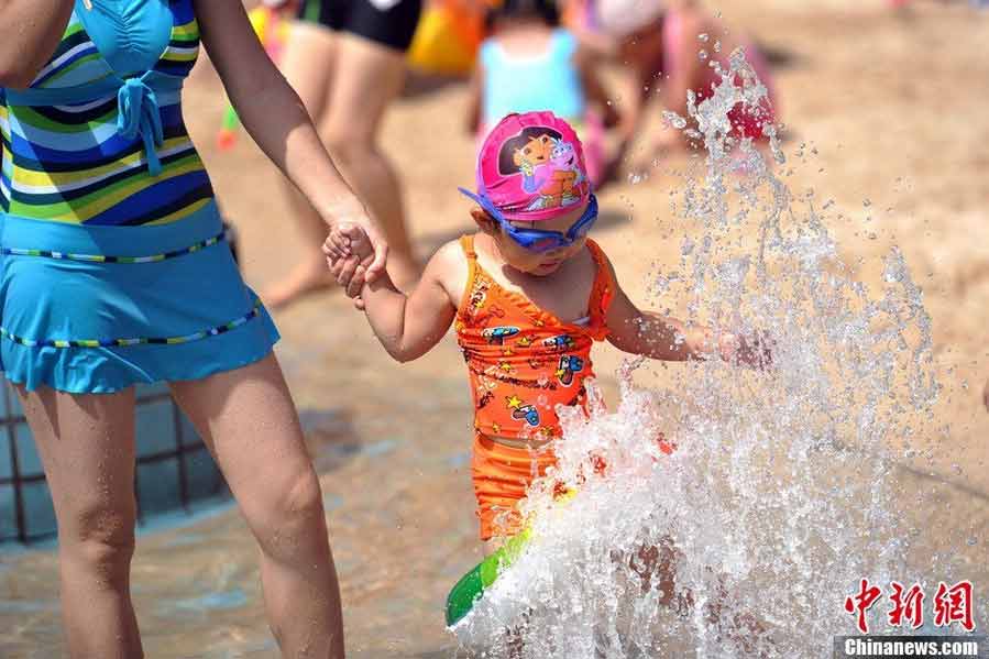 Tourists swarm to the bathing beach in Beijing's Chaoyang Park to escape the stifling heat on July 28, 2013. On the same day, the city's weather authorities issued this summer's second orange high-temperature alert. (Chinanews.com)