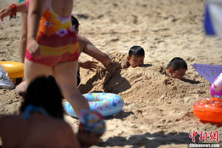 Tourists swarm to the bathing beach in Beijing's Chaoyang Park to escape the stifling heat on July 28, 2013. On the same day, the city's weather authorities issued this summer's second orange high-temperature alert. (Chinanews.com)