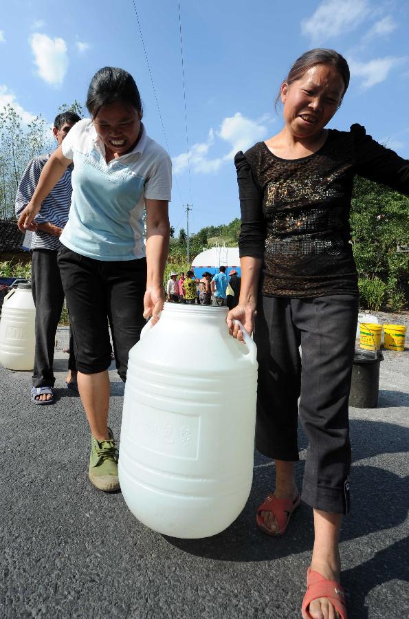 Local residents carry water delivered by government in the Jinba Village of Jinsha County, southwest China's Guizhou Province, July 31, 2013. Lingering droughts in Guizhou have affected more than 12 million people. Over 2 million people lack adequate supplies of drinking water, and a total of 847,300 hectares of farmland is damaged by the drought. (Xinhua/Yang Ying)