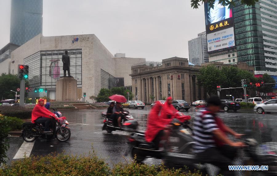 Citizens ride in the rain in Nanjing, capital of east China's Jiangsu Province, July 31, 2013. An artificial precipitation brought coolness to citizens in Nanjing. (Xinhua/He Canling)