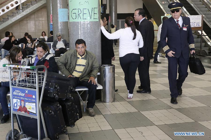 People rest in front of a banner announcing a strike (greve, in Portuguese) of airport workers in the Congonhas airport, in Sao Paulo, Brazil, on July 31, 2013. The strike that began on Wednesday affected the main airports in Brazil, according to local press. (Xinhua/Rahel Patrasso)