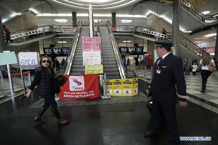 A woman walks in front of banners announcing a strike (greve, in Portuguese) of airport workers in the Congonhas airport, in Sao Paulo, Brazil, on July 31, 2013. The strike that began on Wednesday affected the main airports in Brazil, according to local press. (Xinhua/Rahel Patrasso)