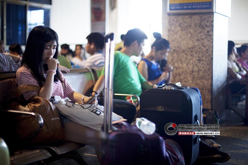 Wu Jia stares at the phone in a waiting room of Zhuhzou railway station, June 25, 2013. Liu Tongwei had not appeared. (XiaoXiang Morning Herald/Jiang Limei)