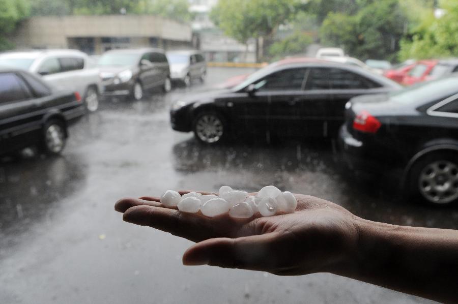 A citizen shows some hailstone picked from the ground in Hangzhou City, capital of east China's Zhejiang Province, Aug. 1, 2013. Hangzhou saw a hail in some of its urban areas on Thursday. (Xinhua/Ju Huanzong) 