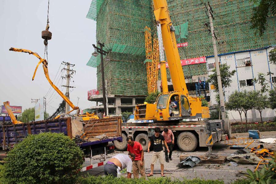 Workers clean the accident scene where the fallen tower crane damaged the prefab houses at a construction site in Xi'an, capital of northwest China's Shaanxi Province, Aug. 1, 2013. Due to sudden thundershower and strong wind, a tower crane at a construction site in Xi'an on early Thursday fell to the prefab houses where lived construction workers, killing four people and hurting four others. (Xinhua/Hou Zhi)