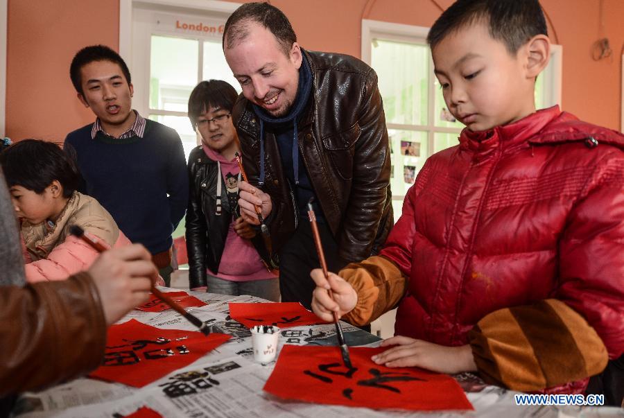Kevin (2nd R), a foreign teacher from the United States, learns writing Chinese character fu, which means happiness, with brush pen at a community in Hangzhou, capital of east China's Zhejiang Province, Jan. 20, 2014. A total of 50 some children and their foreign teacher Kevin celebrated the upcoming Spring Festival through various folk activities on Monday. (Xinhua/Xu Yu) 