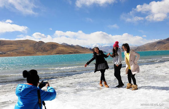 Tourists pose for photos by the side of Yamzho Yumco Lake in Shannan Prefecture, southwest China's Tibet Autonomous Region, Jan. 19, 2014. (Photo/Xinhua)